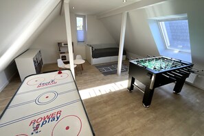 Une pièce avec une table de baby-foot, un lit, une fenêtre et un bureau.