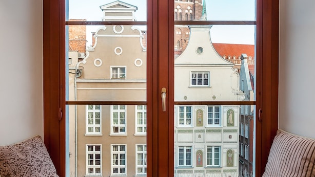 A window seat with a view of historic buildings and a church steeple. - Frey Homes Gdansk Old Town (Gdansk)