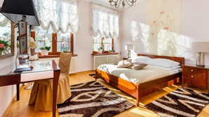 A bedroom with a wooden bed, a glass desk, a chair, a lamp, and a large window with curtains. - Frey Homes Gdansk Old Town (Gdansk)