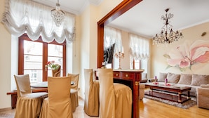 A well-lit living room with a dining area, a sofa set, a TV, and a chandelier. - Frey Homes Gdansk Old Town (Gdansk)
