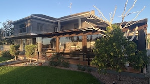 A modern two-story house with a covered patio, a stone fireplace, and a well-maintained lawn. - Luxury villa with detail decorated pool (Zaragoza)