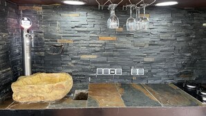 A kitchen with a stone backsplash, a large stone sink, and a wine rack with glasses. - Luxury villa with detail decorated pool (Zaragoza)