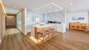 A modern kitchen with a marble backsplash, wooden flooring, and a central island with bar stools. - Vistamar II frontline sea Apt. in a prime location in Puerto Pollensa (Puerto Pollensa)