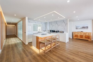 A modern kitchen with a marble backsplash, wooden flooring, and a central island with bar stools.