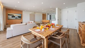 A modern living room with a sofa, wooden dining table, and chairs. - Vistamar II frontline sea Apt. in a prime location in Puerto Pollensa (Puerto Pollensa)
