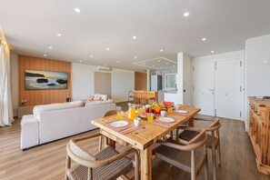Un salon moderne avec un canapé, une table à manger en bois et des chaises.