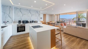 A modern kitchen with a marble backsplash, wooden flooring, and a dining area with a view. - Vistamar II frontline sea Apt. in a prime location in Puerto Pollensa (Puerto Pollensa)