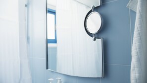 A bathroom with a mirror, a towel rack, and a hand soap dispenser.