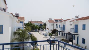 Una calle residencial con edificios blancos, contraventanas azules y tejados de tejas.