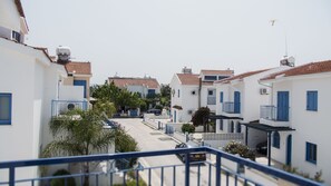 A residential street with white buildings, blue shutters, and tiled roofs.