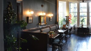 A restaurant with a long counter, seating area, and large windows. - Heatherlie House Hotel (Selkirk)