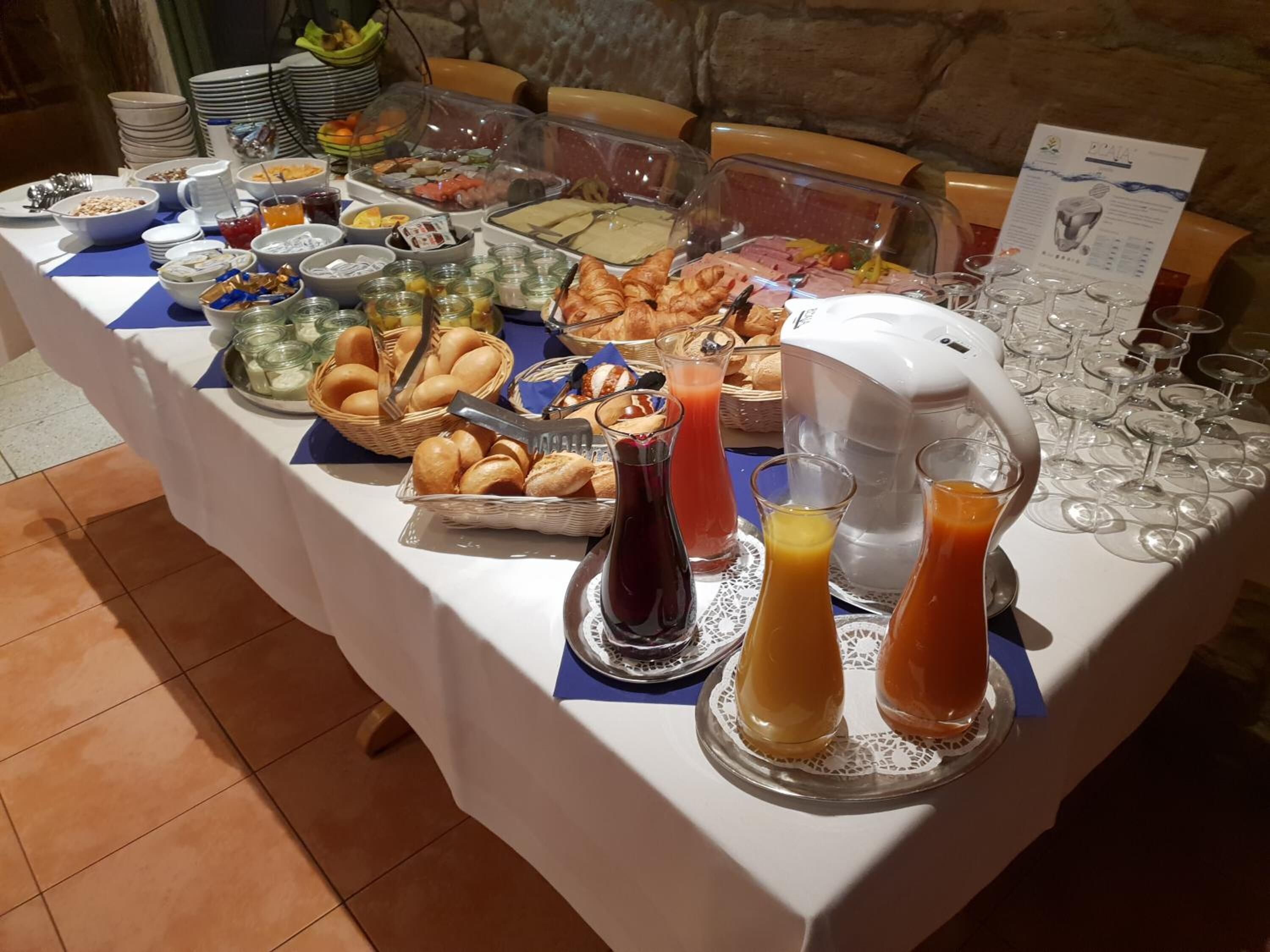 Taula de buffet amb diversos aliments, incloent pa, pastissos i una màquina de cafè.