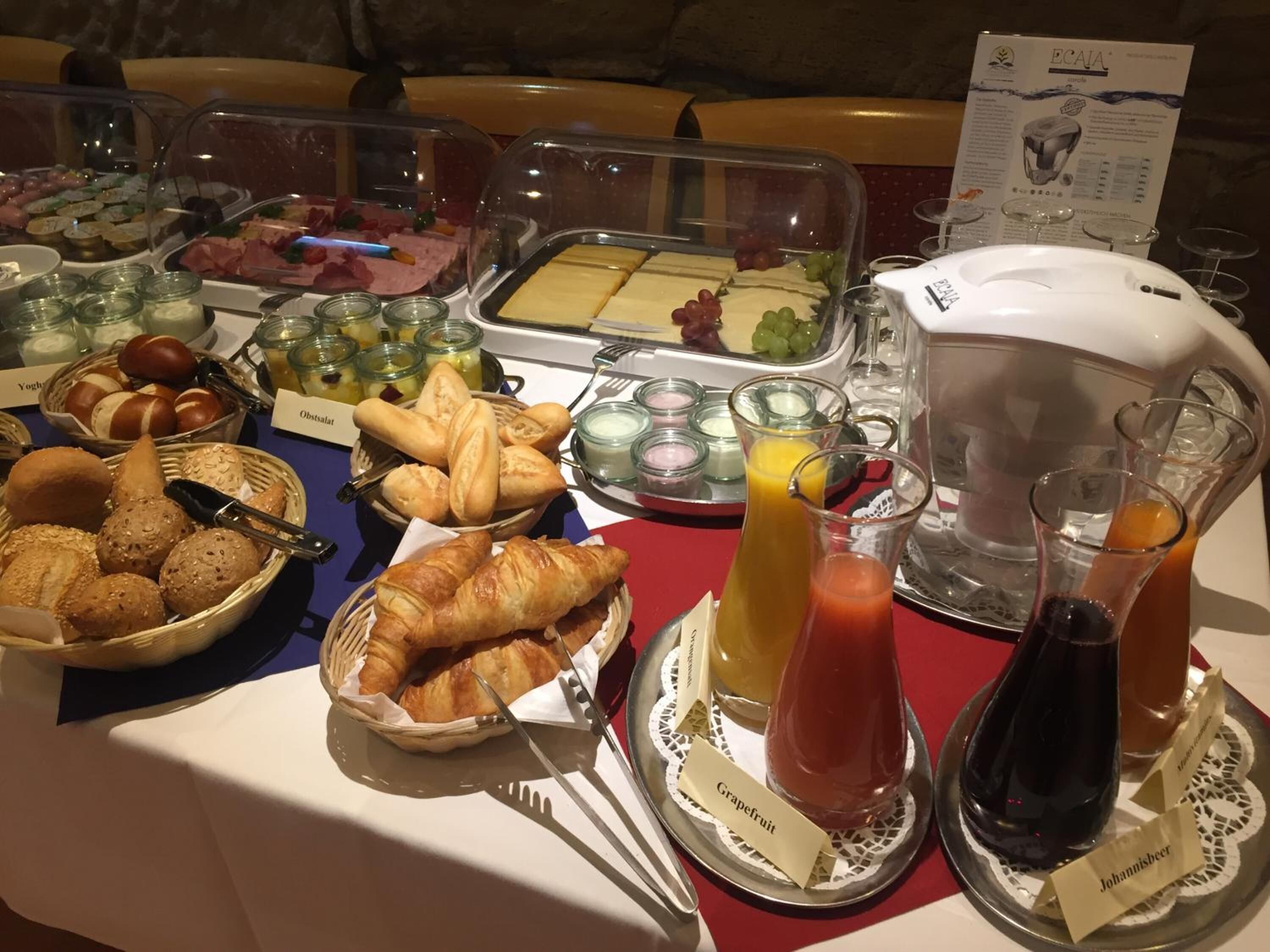 A buffet with various food items and beverages, including bread, pastries, and a selection of juices and wines.