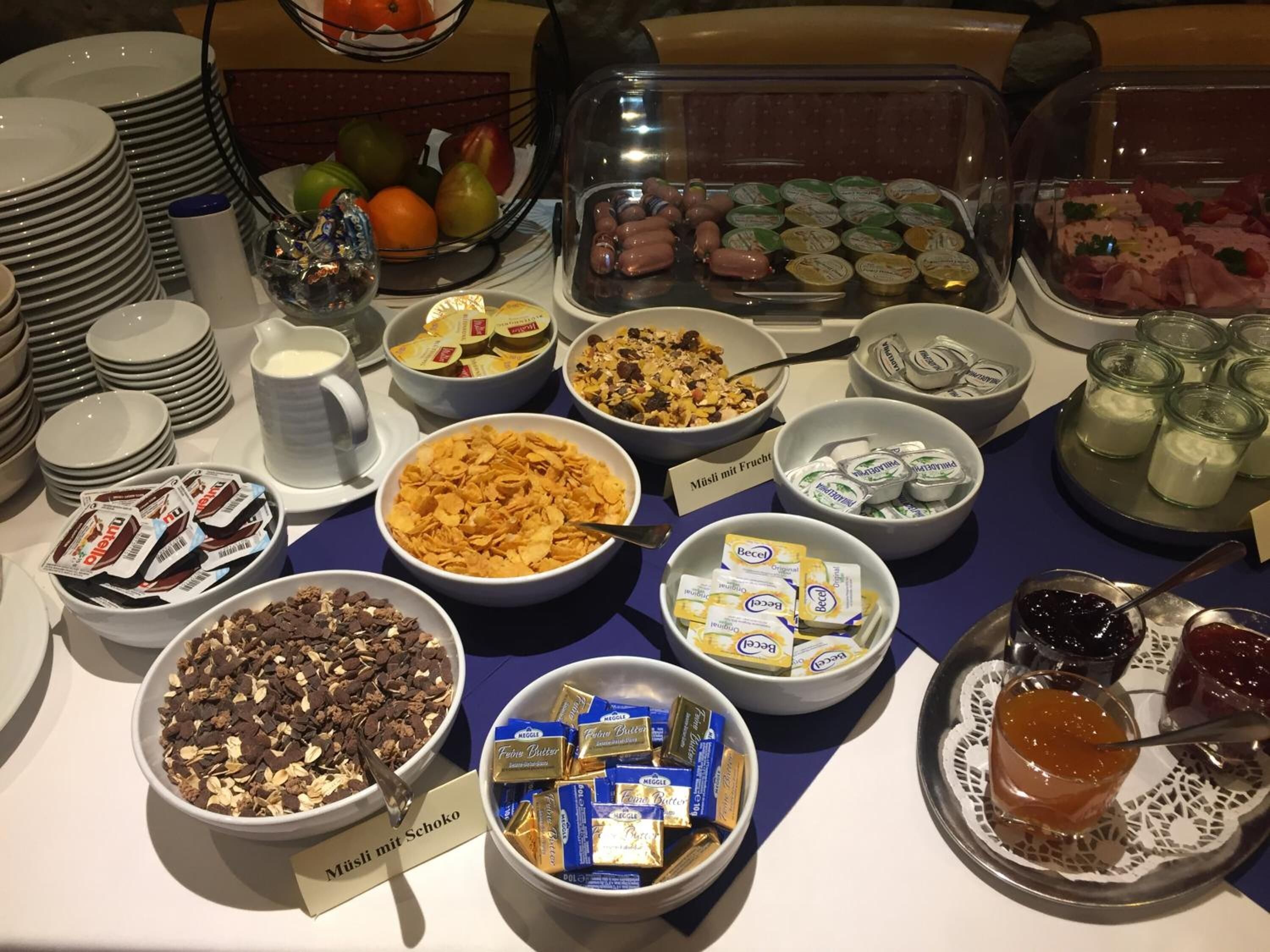 A buffet table with various food items including cereals, chocolates, and condiments.