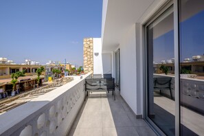 Ein Balkon mit einer Steinmauer, einer Glastür und Blick auf die Stadtlandschaft.