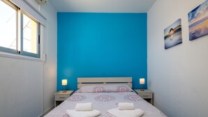 A bedroom with a bed, two bedside tables, a window, and two wall-mounted pictures. - Anonymous - 2BR - 2Floors - Central (Ayia Napa)