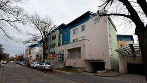 Een meerlaags woongebouw met een plat dak, een garage-ingang en een voetpad.