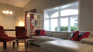 Ein Wohnzimmer mit einer Couch, Sesseln, einem Couchtisch und einem Fenster mit Aussicht.