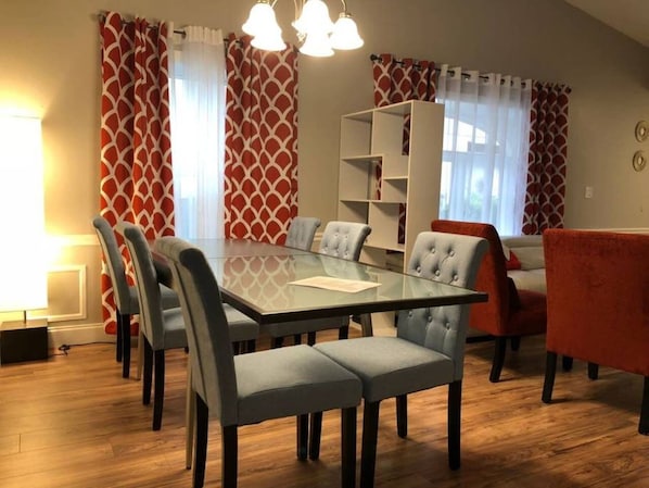 En matplats med ett glasbord, grå stoppade stolar och en röd soffa.