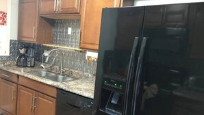 Eine Küche mit Holzschränken, einem Edelstahl-Kühlschrank, einer Kaffeemaschine und einem Wasserspender.