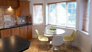 Une cuisine moderne avec une table ronde en verre, des chaises jaunes et des meubles de rangement en bois.
