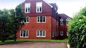 Un bâtiment en briques rouges, doté de nombreuses fenêtres et d’un toit en pente.