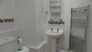 Une salle de bain avec un lavabo blanc, un miroir et un porte-serviettes.