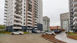 Ein moderner Apartmentkomplex mit mehreren Hochhäusern, einem Parkplatz mit Autos und einem angelegten Pfad.