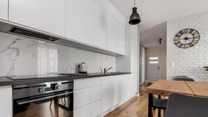 Eine moderne Küche mit weißen Schränken, einer Marmor-Spritzschutzleiste und einem Holzespeisetisch mit Stühlen.