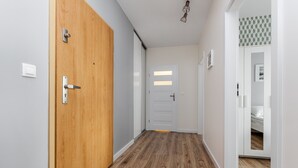 Ein Korridor mit Holzboden, einer Holztür und einer weißen Tür mit horizontalen Füllungen.