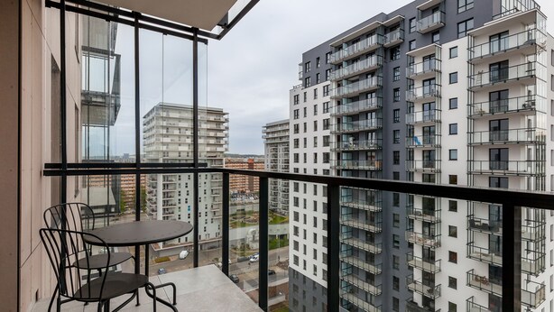 Ein Balkon mit Tisch und Stühlen, der auf einen Stadtblick mit hohen Gebäuden blickt.