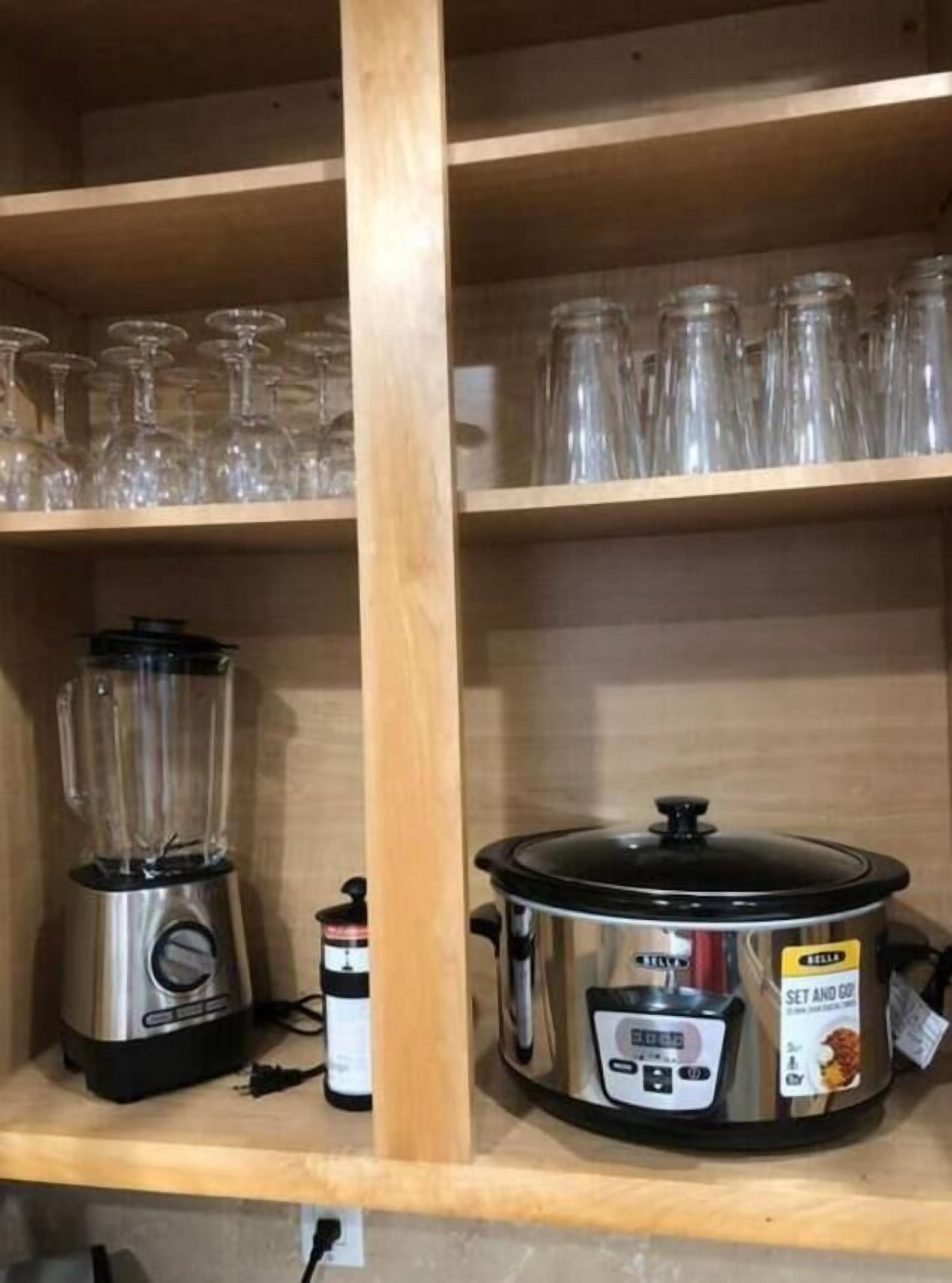 A kitchen shelf with a blender, a slow cooker, and several glass jars.
