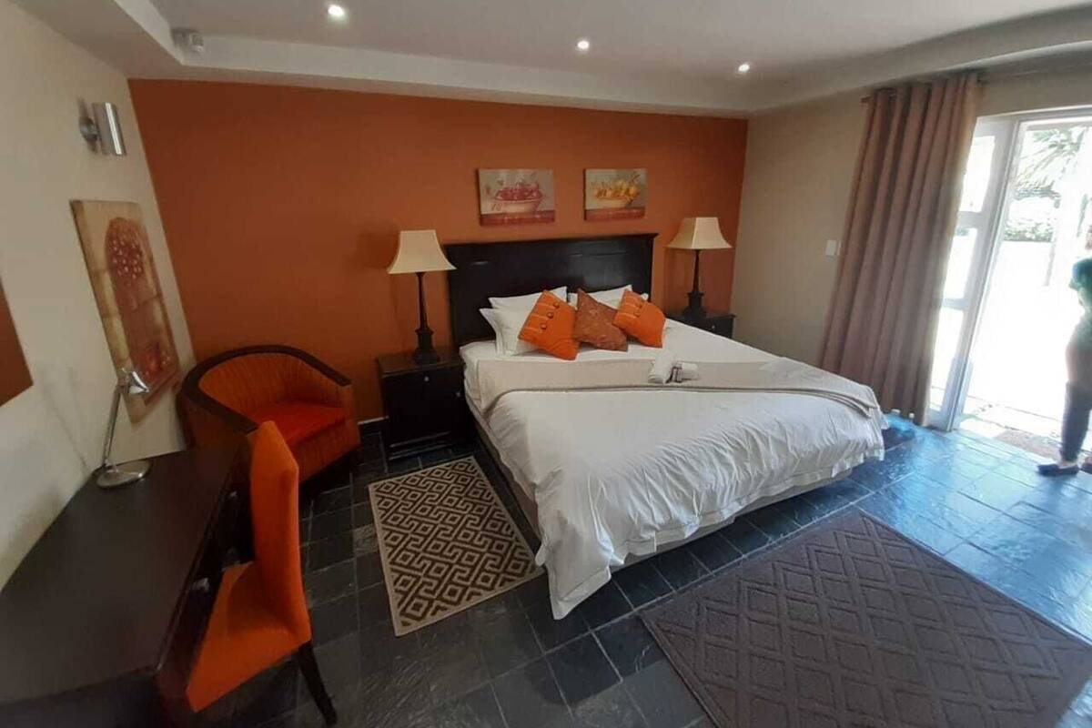 Una habitación de hotel con una cama grande, dos mesitas de noche, una silla y una obra de arte en la pared.