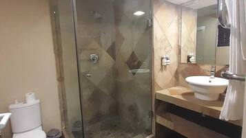 A bathroom with a glass-enclosed shower, a toilet, a sink, and a mirror.