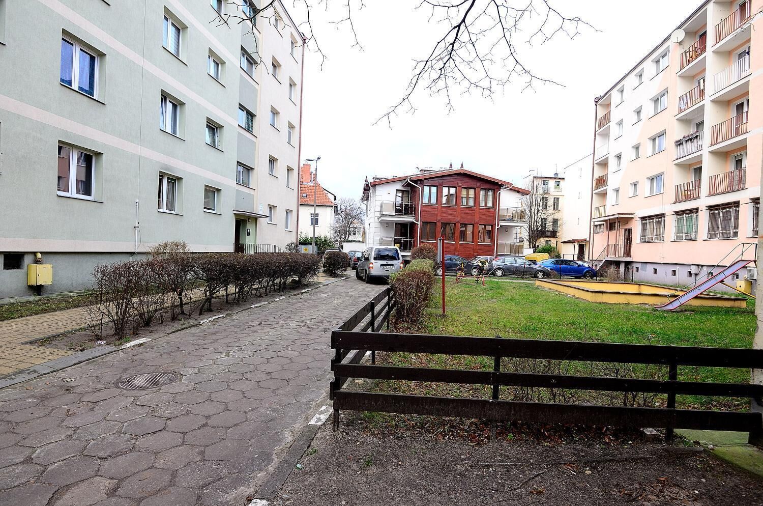A residential street with apartment buildings, a playground, and a bench.