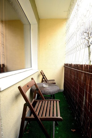 A corner with a wooden bench, a wicker table, and a window. - Victus Apartamenty - La Figure (Sopot)