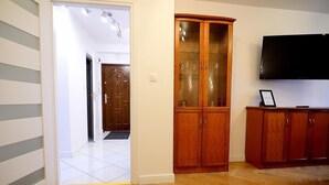 Een woonkamer met een houten kast, een televisie en een deur naar een andere kamer.