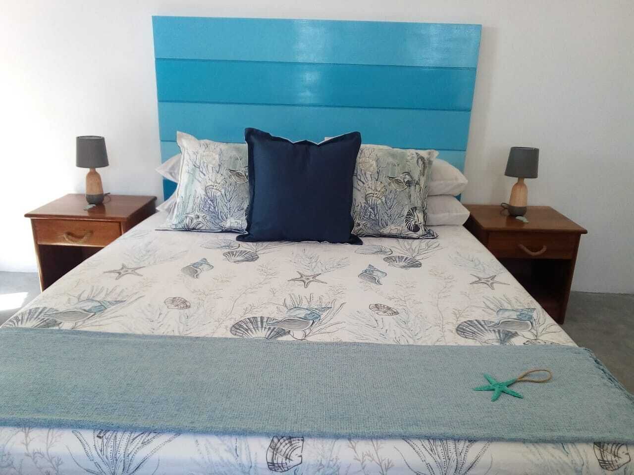 A bed with a blue headboard, two nightstands, and a floral-patterned bedspread.