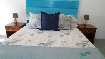 A bed with a blue headboard, two nightstands, and a floral-patterned bedspread.