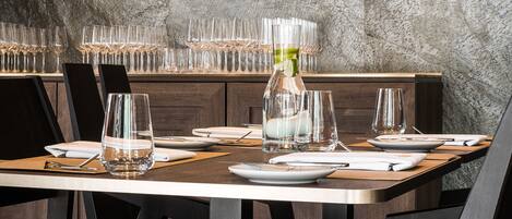 A dining area with a round table set for four, surrounded by chairs, against a textured wall.