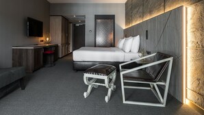 Una habitación de hotel moderna con cama, escritorio, silla y televisión.