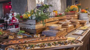 A buffet with various food items and decorations, including wooden serving boards, a Christmas tree, and a pumpkin centerpiece.
