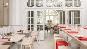 Un comedor amplio con techos altos, ventanas grandes y una larga mesa dispuesta para una comida.