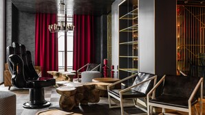 Un interior moderno con un sofá de cuero negro, una mesa de centro de madera y una cortina roja.