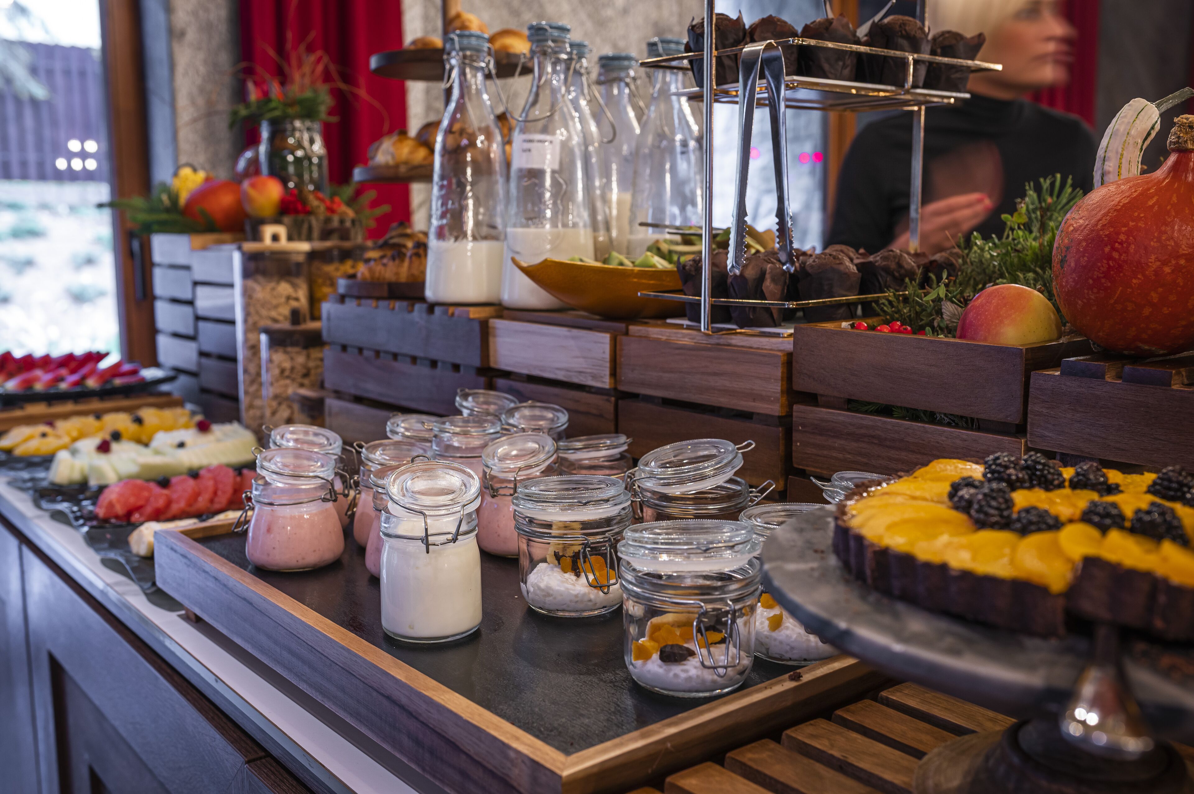 Un buffet proposant une variété de plats et de boissons, notamment des pots de lait et une grosse citrouille.