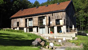 A rustic wooden house with a sloped roof, large windows, and a stone foundation. - Młyn Klekotki spa resort (Gmina Godkowo)