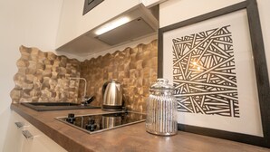 A kitchen with a textured backsplash, a stainless steel kettle, a glass jar, and a framed abstract artwork. - Frey Homes City Centre Plac Zbawiciela (Warsaw)