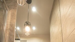 A bathroom with a large white sink, a mirror above it, and a hanging light fixture. - Frey Homes City Centre Plac Zbawiciela (Warsaw)