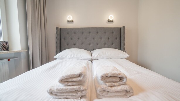 A neatly made bed with two pillows and two folded towels in the center. - Frey Homes City Centre Plac Zbawiciela (Warsaw)