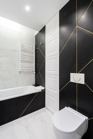 Ein modernes Badezimmer mit einer weißen Badewanne, einer Toilette und einem Handtuchhalter.